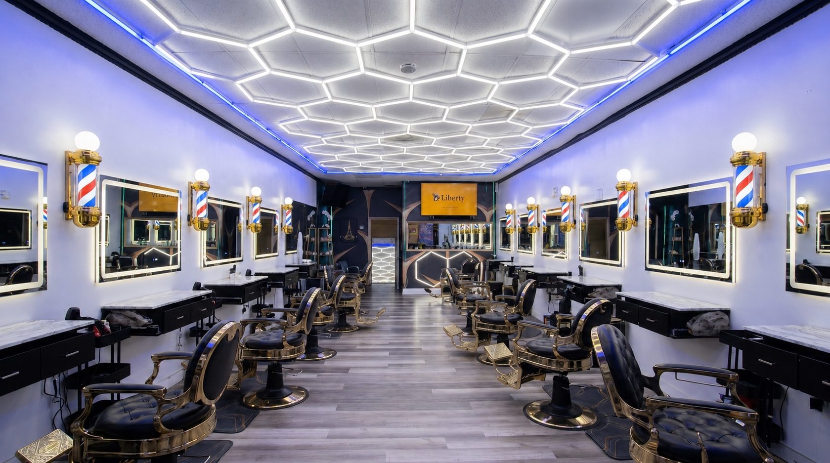 Rony's The Barbershop with white mirror lights, blue LED ceiling light, and black and gold barber chairs